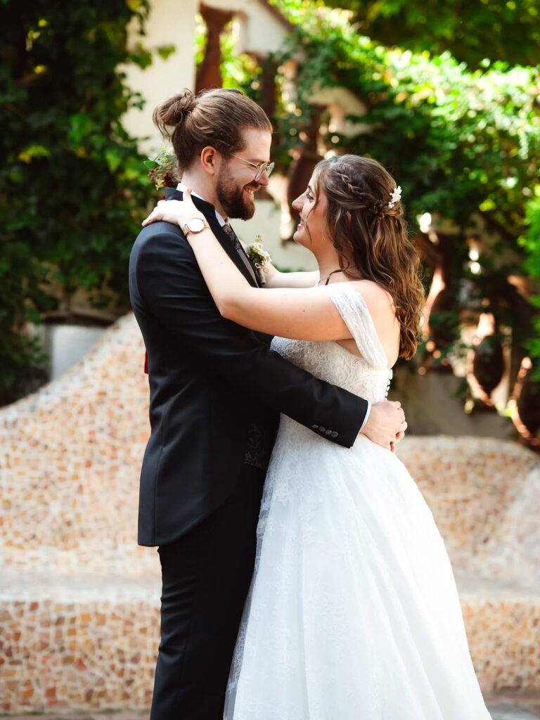 Pareja de novios abrazada en un patio con vegetación, fotografiada por David Photographerx