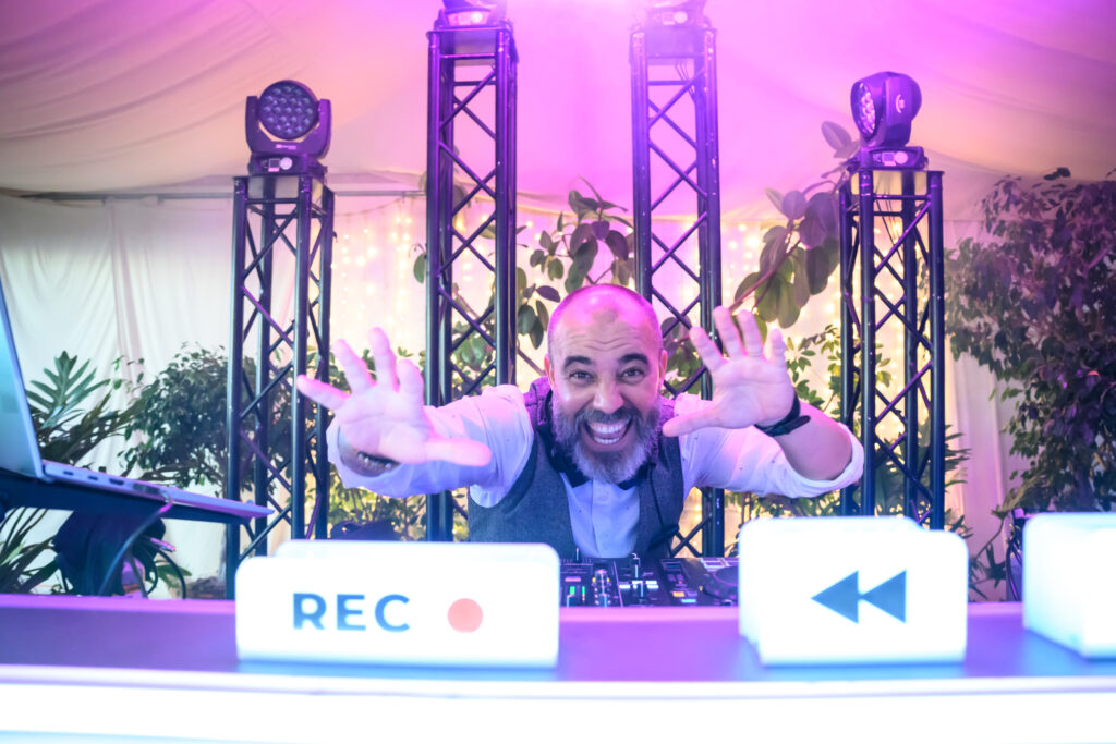 DJ profesional mezclando música en boda con equipo Pioneer y luces de escenario en Tenerife