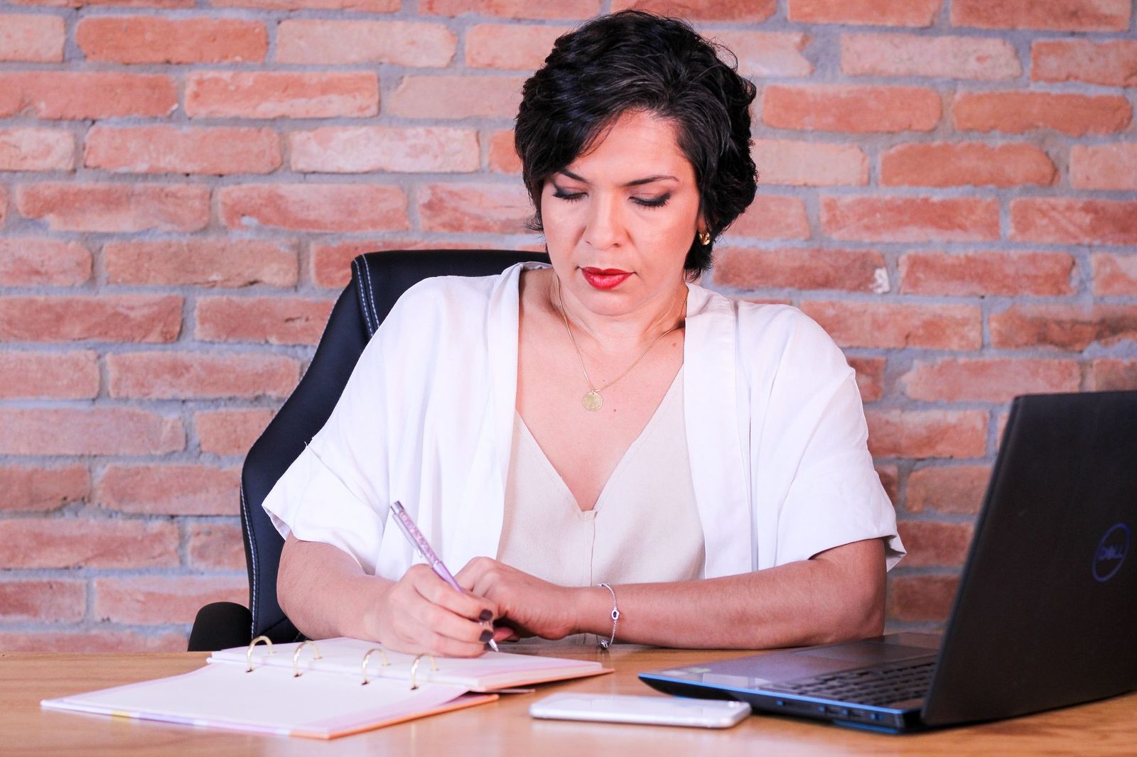 Proveedora de bodas revisando una solicitud en su estudio con una computadora y una libreta.